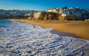 Winter light in Portugal at Albufeira’s sandy beach in Portugal. City view from the beach. Waves.